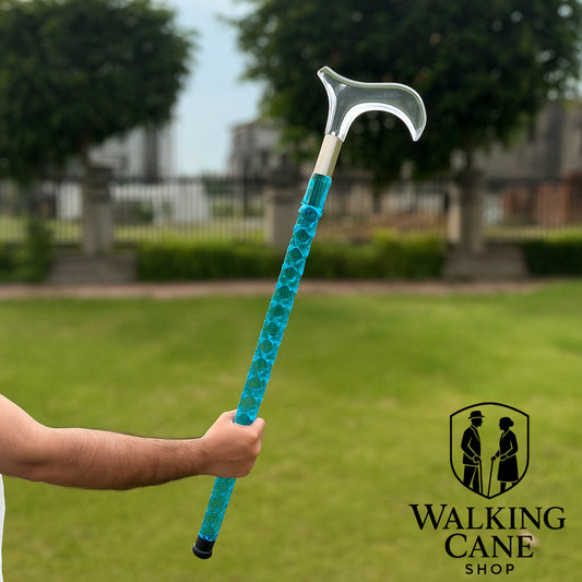 Blue walking cane held by a person with a blurred outdoor background, featuring the Walking Cane Shop logo.